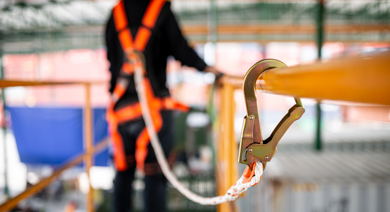 Image of a worker on a lift using a harness for satety. 